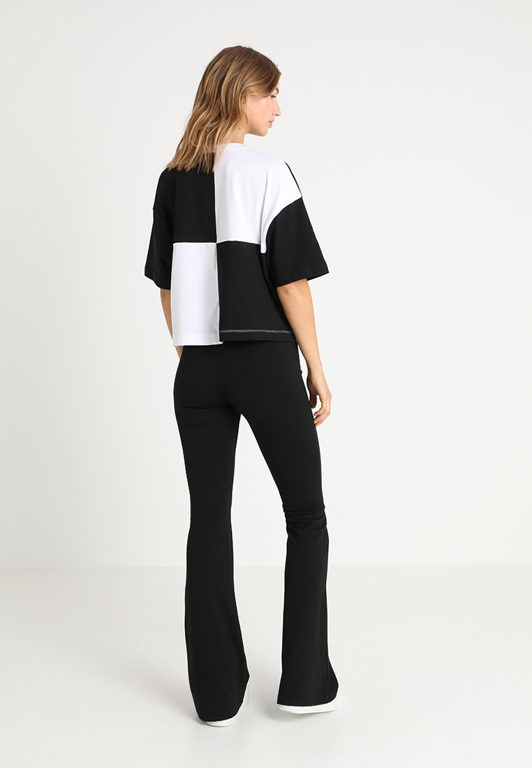 Czarny i biały, kolorowy blokowany, krótki t-shirt z krótkimi rękawami, zestawiony z czarnymi spódnicami dzwonami i białym obuwiem. Gładka faktura materiału.