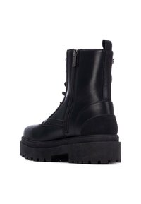 Botas de tobillo negras hechas de cuero y ante, con una suela de plataforma gruesa, cremallera lateral, cordones en la parte delantera y diseño de punta redonda.