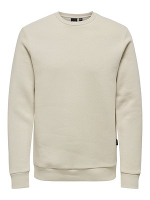 Bež dukserica s okruglim izrezom, dugim rukavima, rebrastim manžetama i rubom, izrađena od mekog materijala, bez vidljivih logotipa ili uzoraka.