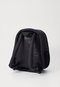 Mochila acolchada negra de nailon con forma estructurada, que cuenta con correas ajustables dobles y cierre de cremallera. Textura suave.