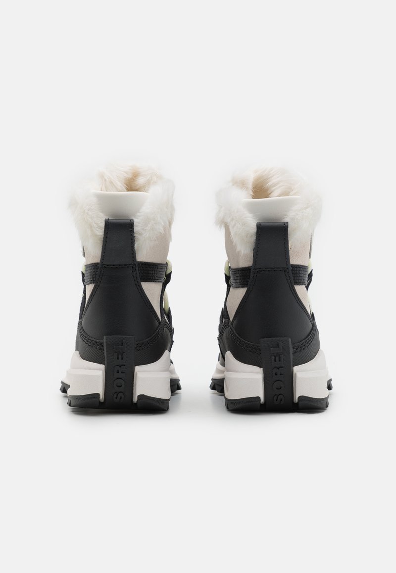 Schwarze und cremefarbene Winterstiefel mit einem gefälschten Pelzkragen, strukturiertem Stoff, gepolstertem Kragen und einer weißen Gummisohle mit Branding an der Rückseite.