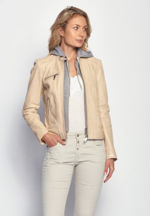 Beige Lederjacke mit grauem Kapuzen, Reißverschluss und seitlichen Taschen. Strukturelle Details an den Schultern und metallische Akzente.