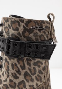 Botín de ante con estampado de leopardo, con una correa de cuero negra con ojales y una placa de metal con el logo de "Pepe Jeans" cerca del borde superior.