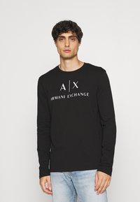 Black long-sleeve shirt made of cotton, featuring a white "Armani Exchange" logo across the chest and a round neckline.