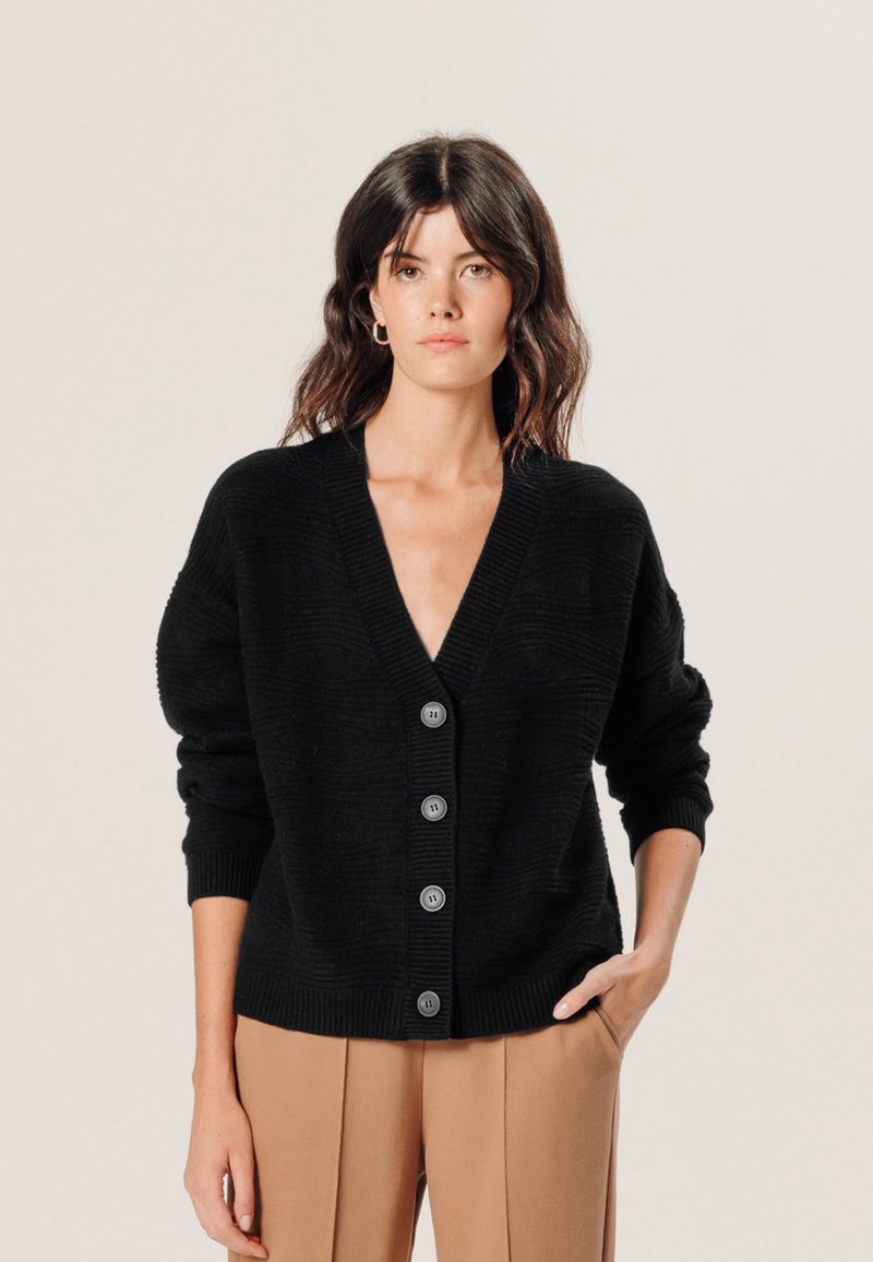 Schwarze Strickjacke mit tiefem V-Ausschnitt, langen Ärmeln und fünf Knopfverschlüssen. Sie hat strukturierte Muster sowie gerippte Bündchen und Saum.