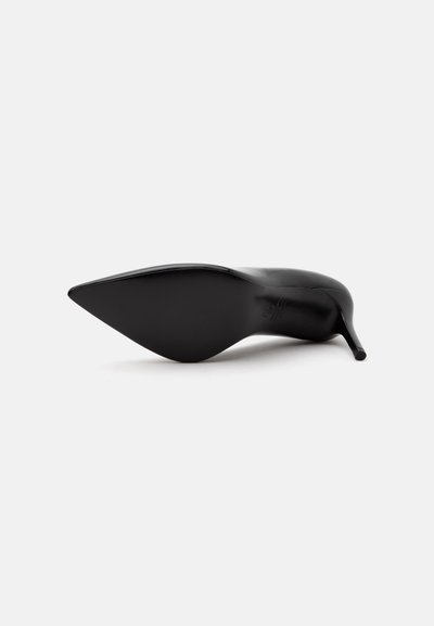 Chaussure à talon haut noire à bout pointu vue par la semelle avec un talon aiguille fin sur fond blanc.