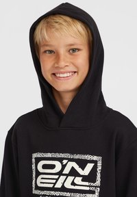 Sudadera negra con un gráfico blanco de "O'Neill". Presenta una capucha grande, una textura suave y puños acanalados en las mangas.