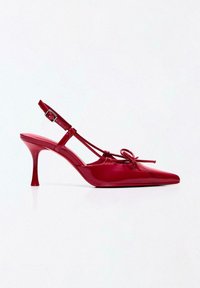 Rode slingback schoenen van lakleer met een spitse neus, dunne hak en een strikdetail aan de voorkant. Verstelbare enkelband met gesp.