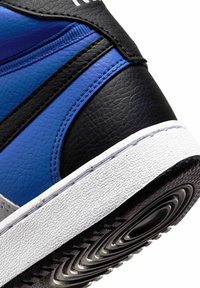 Sneaker alta con pannelli in pelle blu, nera e grigia, superficie texturizzata, suola in gomma bianca e battistrada a motivo.