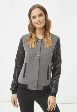 Chaqueta bomber gris con mangas de cuero negro, botones a presión y bolsillos laterales. Presenta puños y dobladillo acanalados, tela texturizada y un diseño elegante.