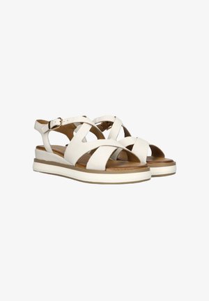 Sandales blanches en cuir avec des brides croisées, une fermeture à boucle à l'arrière, et une semelle à plateforme superposée avec une texture ressemblant à du bois et des accents blancs.