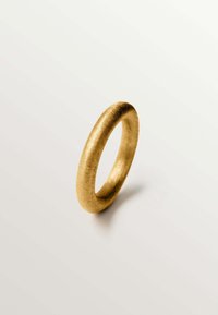 Anillo de oro con una textura suave y cepillada, que presenta un diseño simple y redondeado. Exhibido sobre un fondo claro, lo que enfatiza su color y forma.