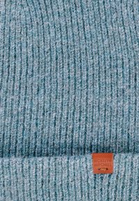 Jasnoniebieska dziana czapka z prążkowanym teksturą, z brązową skórzaną metką wytłoczoną napisem "BICKLEY + MITCHELL."