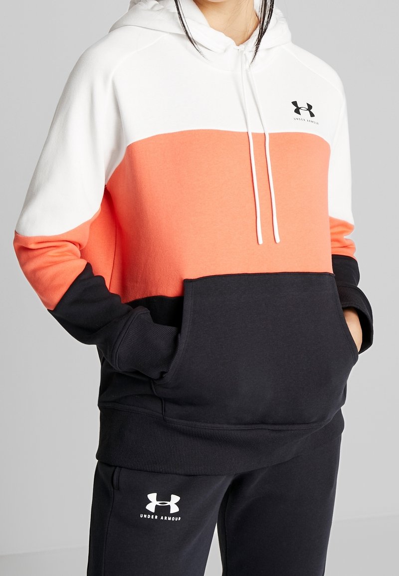 Sudadera con bloques de color en segmentos blanco, coral y negro; cuenta con un bolsillo frontal, cordones ajustables y un tejido suave.