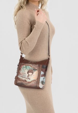 Braune Schultertasche mit grafischem Design und dem Text "Der BEAT der Erde." Glattes Leder mit verstellbarem Tragegurt.