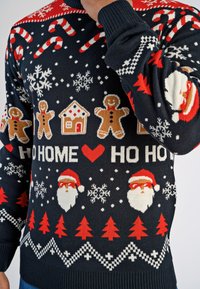 Stickad tröja i marinblått med julmotiv: godisbitar, snöflingor, pepparkaksgubbar, tomteansikten, röda träd och festlig text.