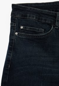 Jeans de mezclilla oscura con cintura alta, que cuentan con dos bolsillos frontales, remaches de metal y costuras a tono. Textura suave, corte clásico.
