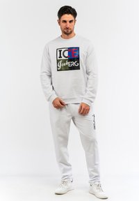 Sweatshirt grigio con una grafica multicolore "ICE" e "Iceberg". Abbinato a pantaloni giapponesi grigi coordinati con stampa del logo laterale e polsini elasticizzati.