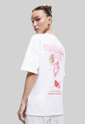 Hvid bomulds t-shirt med en pink grafik af et cocktailglas med jordbær, akkompagneret af tekst i en legesyg skrifttype på bagsiden.