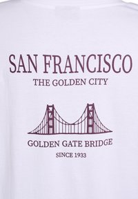 Valge T-särk, millel on burgundivärviline tekst "San Francisco The Golden City" ning üle selle on kujutatud Golden Gate'i silda ja tekst "Since 1933."