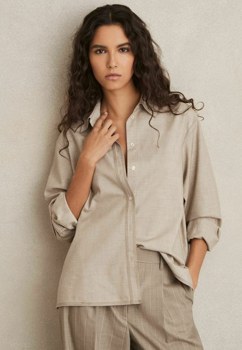 Lichtbruine, losvallende button-up shirt met een kraag en opgerolde mouwen. Gemaakt van een gestructureerde stof, gecombineerd met bijpassende gestreepte broek.