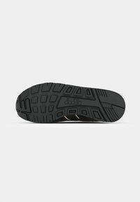 Black rubber shoe sole features deep tread patterns and a smooth finish, with a logo prominently displayed in the center.