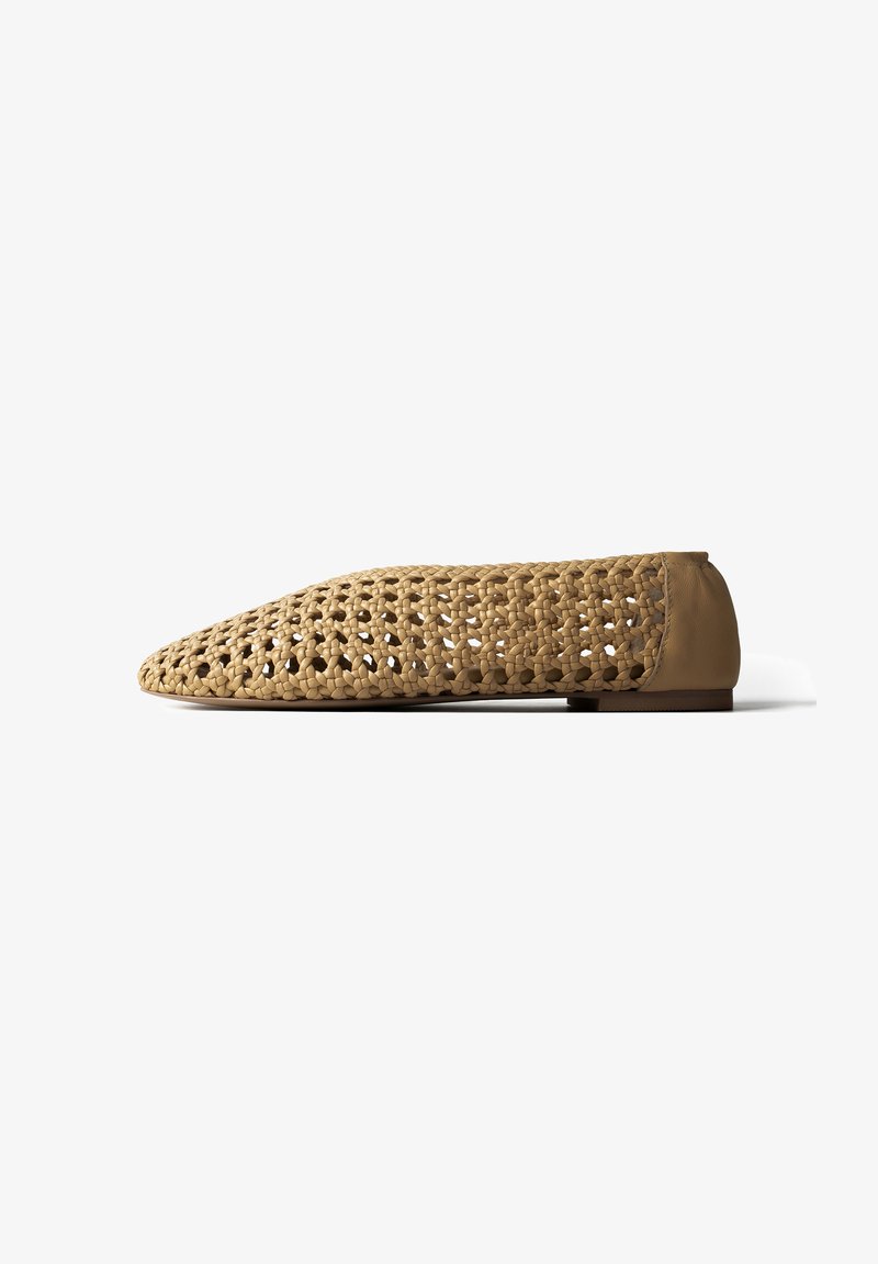 Chaussure plate marron clair avec un motif tricoté ouvert et une section de talon solide, vue de profil sur fond blanc.