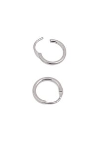 Srebrne metalowe kolczyki w kształcie obręczy, o okrągłej formie, gładkiej teksturze, z małym otworem do zapięcia, odbijające światło.