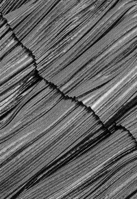 Tissu en mesh noir avec de fines lignes texturées créant un motif en couches. Présente des sections transparentes et un bord irrégulier le long de la couture.