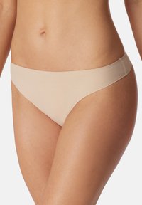 Tanga senza cuciture in tonalità nude realizzato in tessuto morbido, con una vita bassa e un design minimalista per comfort e indossabilità discreta.