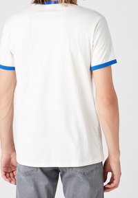 Vit T-shirt med blå ribbad krage och ärmar, med korta ärmar och vanlig passform, tillverkad av mjukt bomullstyg.