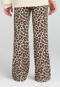 Pantaloni a zampa d'elefante in stampa leopardata beige, con macchie nere e marroni. Realizzati in tessuto morbido con una vita elasticizzata e vestibilità rilassata.