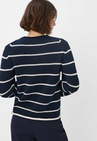 Navyblauwe trui met witte horizontale strepen. Geribbelde textuur, ronde hals en gewatteerde schouders. Gebreide stof met contrasterende zoomdetails.