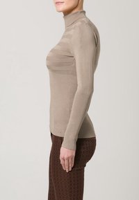 Maglione beige a collo alto con texture a coste, caratterizzato da un design aderente e righe orizzontali sul petto e sulle maniche.