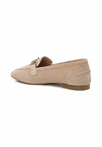 Mocasines de ante beige sin cordones con punta redondeada, acento decorativo de hebilla, tacón bajo apilado y costuras visibles a lo largo de las costuras.