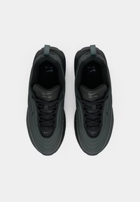 Egy pár sötétszürke Nike Air sportcipő, felülnézetből, fehér háttér előtt, bemutatva a fűzőt és a logórészleteket a nyelveken és a talpbetéteken.