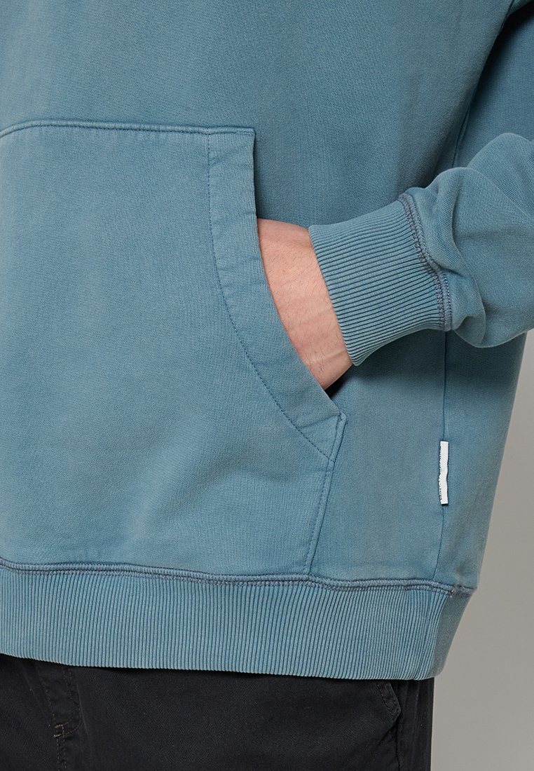 Hellblaues Sweatshirt mit einer Kängurutasche, gerippten Bündchen und Saum. Das Material wirkt weich mit einer feinen Textur und sauberen Nähten.