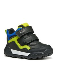 Zapatilla deportiva negra y verde con un diseño texturizado, que cuenta con dos correas de velcro, una suela de goma y acentos azules en el talón.