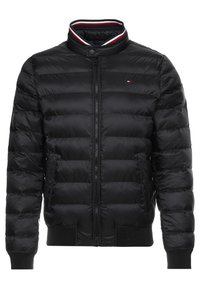 Doudoune noire avec fermeture éclair sur le devant, col et poignets côtelés. Présente un rembourrage horizontal et un petit logo sur la poitrine.