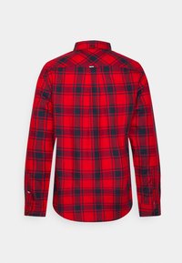 Chemise à manches longues rouge et noire à carreaux avec des poignets boutonnés, présentée de dos sur fond blanc uni.