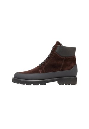 Botas de tobillo de ante marrón con una suela de goma negra y acentos de cuero texturizado. Presentan un diseño con cordones y un collar aislante.