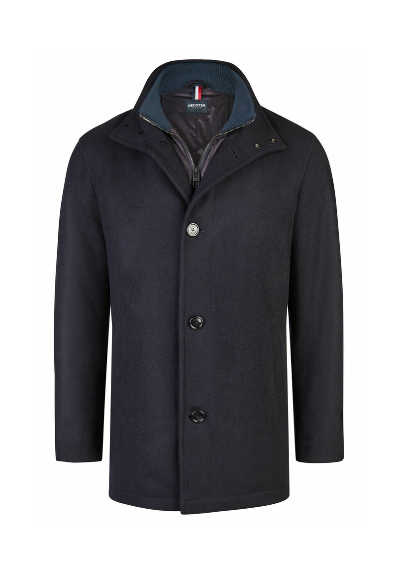 Tamsiai mėlynas paltas su stovinčia apykakle, priekyje užtrauktukas, spaudės mygtukai ir dvi šoninės kišenės; pagamintas iš lygaus tekstūruoto audinio.