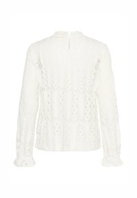 Blusa bianca in pizzo con motivi intricati, maniche lunghe con polsini a volant, collo alto e chiusura a oblò nella parte posteriore.