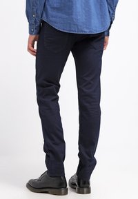 Laivastonsinisiä slim-fit-housuja, jotka on valmistettu puuvillasta ja joissa on sileä pinta, viisi taskua ja huomaamattomat ompelu yksityiskohdat.