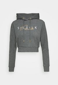 Sudadera gris recortada hecha de una tela suave que presenta una capucha con cordón y un logo con detalles en dorado en el frente. Mangas largas con puños de canalé.