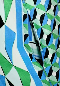 Bunt gemustertes Gewebe mit geometrischen Mustern in Grün, Blau, Schwarz und Weiß. Das Design enthält scharfe Winkel und glatte Texturen.