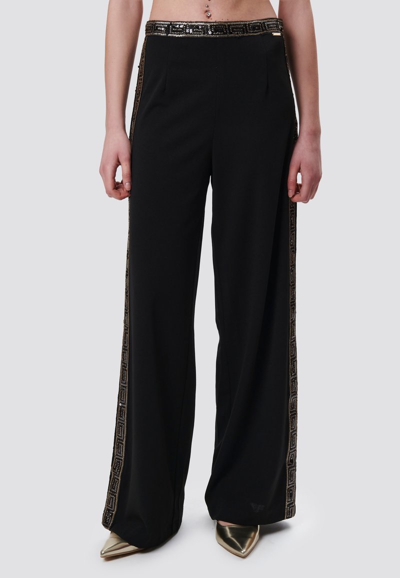 Zwarte high-waisted broek met een wijde pijpdesign, voorzien van een glanzende gouden tailleband en gestreepte zijstrips.