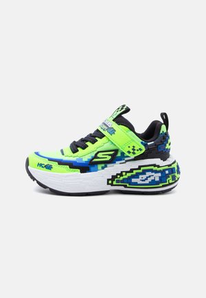 Bright green and blue kids' sneaker with pixelated design, black laces, velcro strap, and thick white sole with graphic patterns.
