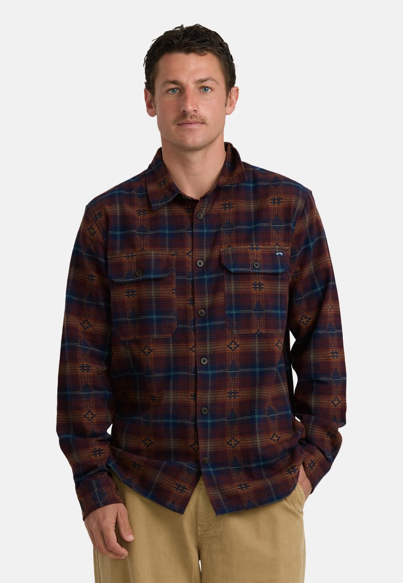 Geruite flanellen shirt in rood, bruin en blauw. Heeft twee borstzakken en een patroonontwerp. Lange mouwen met knopenmanchet.