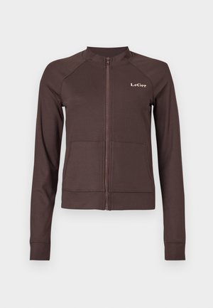 Casaco castanho com fecho de correr, textura canelada, mangas raglan e logótipo. Apresenta dois bolsos frontais e punhos e bainha ajustados.